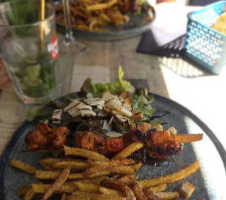 Brochettes grillées et frites coupées maison sur une assiette en grès, copeaux de parmesan et roquette.